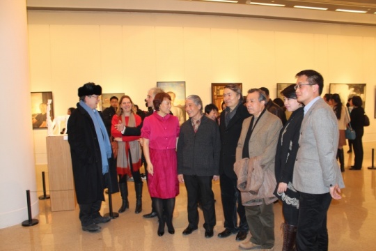 赞助人邓喜红（枚红色裙装）与艺术家一起观看展览
