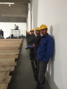 站在展厅两边的工人们，刚刚结束搭建作品“地”的最后一道工序