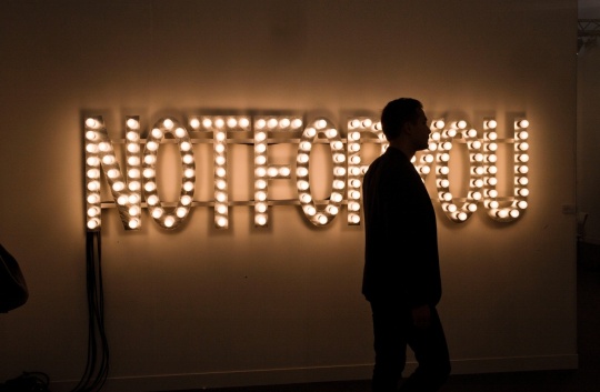 A visitor wanders by a Not For You neon at Frieze London.Photograph Sarah Lee/the Guardian.