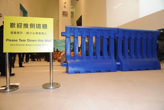 关尚智的作品《水马》茅台与水以1：999的比例注入蓝色装置之中，在展览大厅的入口处，摆放着热情的提示语：欢迎推倒这墙