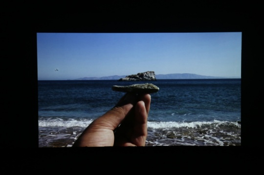 井上小金沢《直至录像带结尾》，不禁怀疑，画面中的这只手是要捡到一块和远处小岛轮廓相同的石头吗？
