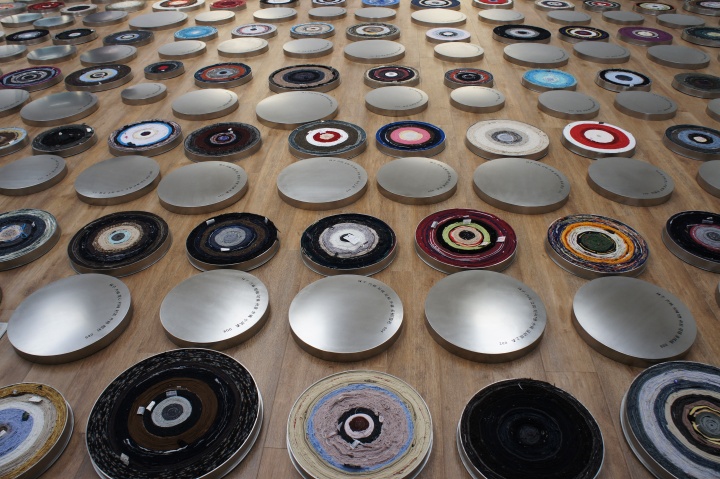 《一句话》装置   不同人穿过的衣服、不锈钢 2011  （横滨三年展） ，尹秀珍将108件个人的衣服拆开，再重新缠绕成电影胶卷一样的卷轴，放在摆放成螺旋形的圆盒中。
