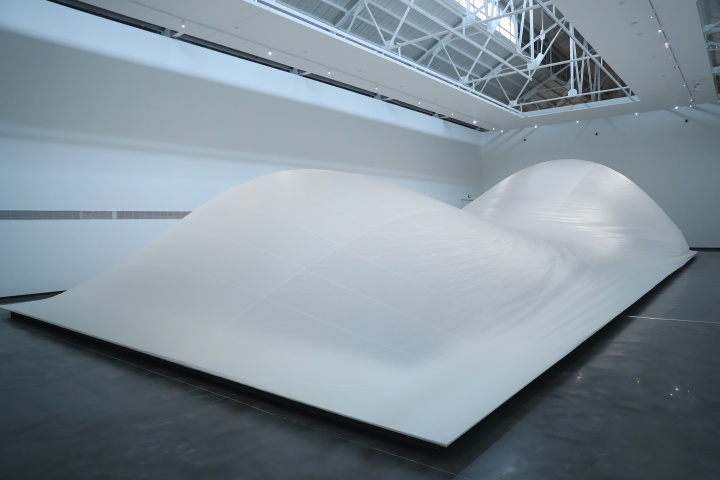 进入展厅后的第一件作品《流动的风景》由艺术家根据美术馆空间特别设计，其表面覆盖的半透明布料是芬兰人用于制作船帆的帆布，帆布的下面隐藏了一个鼓风机，气体逐渐填满再慢慢地泄出去，整个装置仿佛在不停呼吸。

《流动的风景》 24.4×11×3.5m 聚酯布、万花板、木材、风扇、数字调光器、电脑 2020
